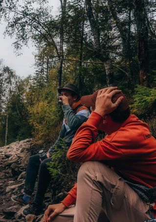 Two hikers in vibrant autumn forest pause along the rocky trail, capturing the beauty of nature.