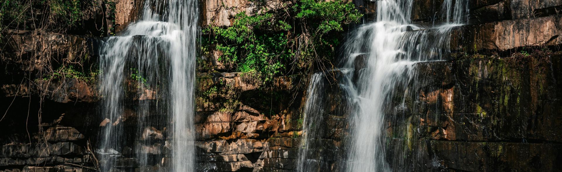 A serene waterfall cascading over rocks in the lush forest of Thailand.