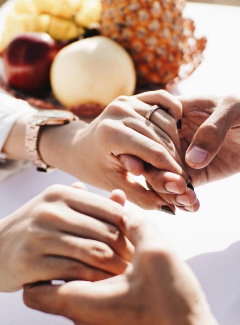 Close-up of a couple holding hands outdoors with fruits nearby, conveying love and affection.