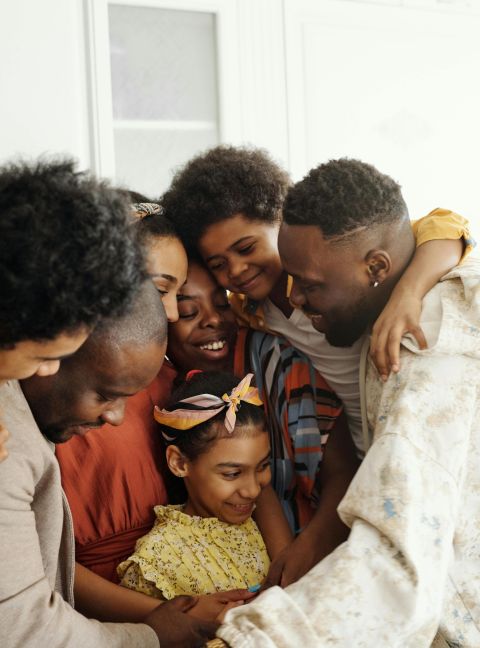 A heartwarming moment of diverse family members embracing indoors, exuding joy and togetherness.