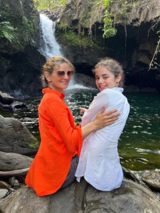 A family of four holds hands while facing the ocean, enjoying a peaceful day at the beach.